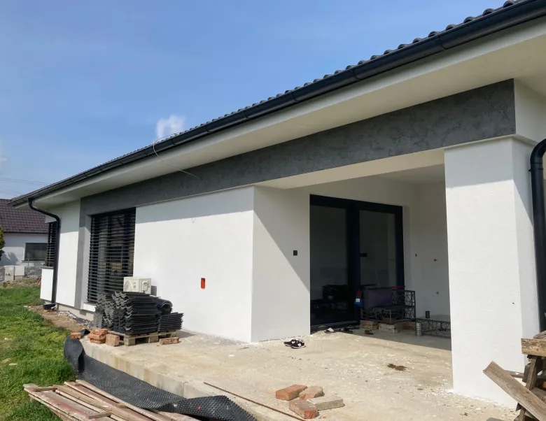 Modern bungalow with a white facade and fair-faced-concrete effect